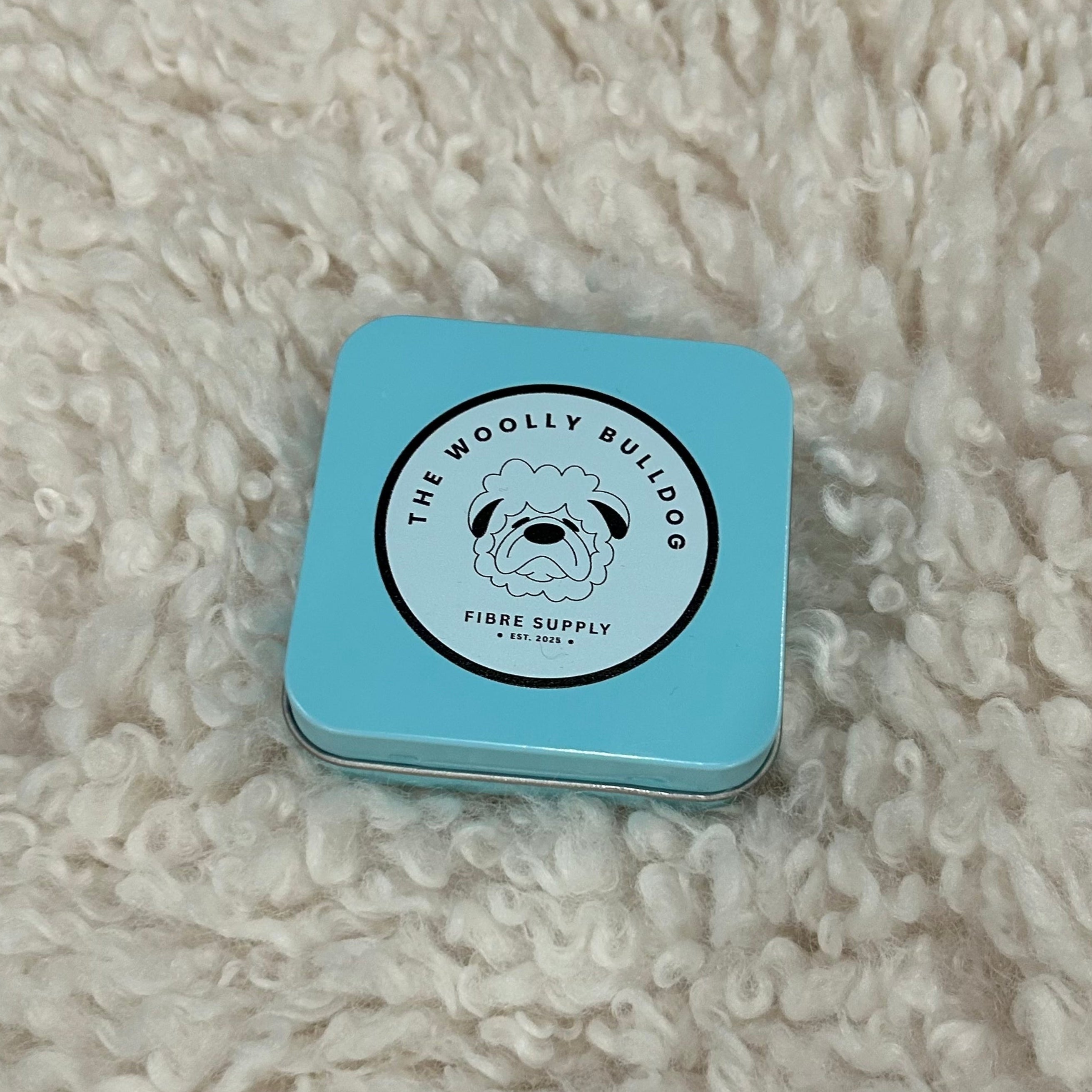 Blue tin box with a logo on a textured white surface