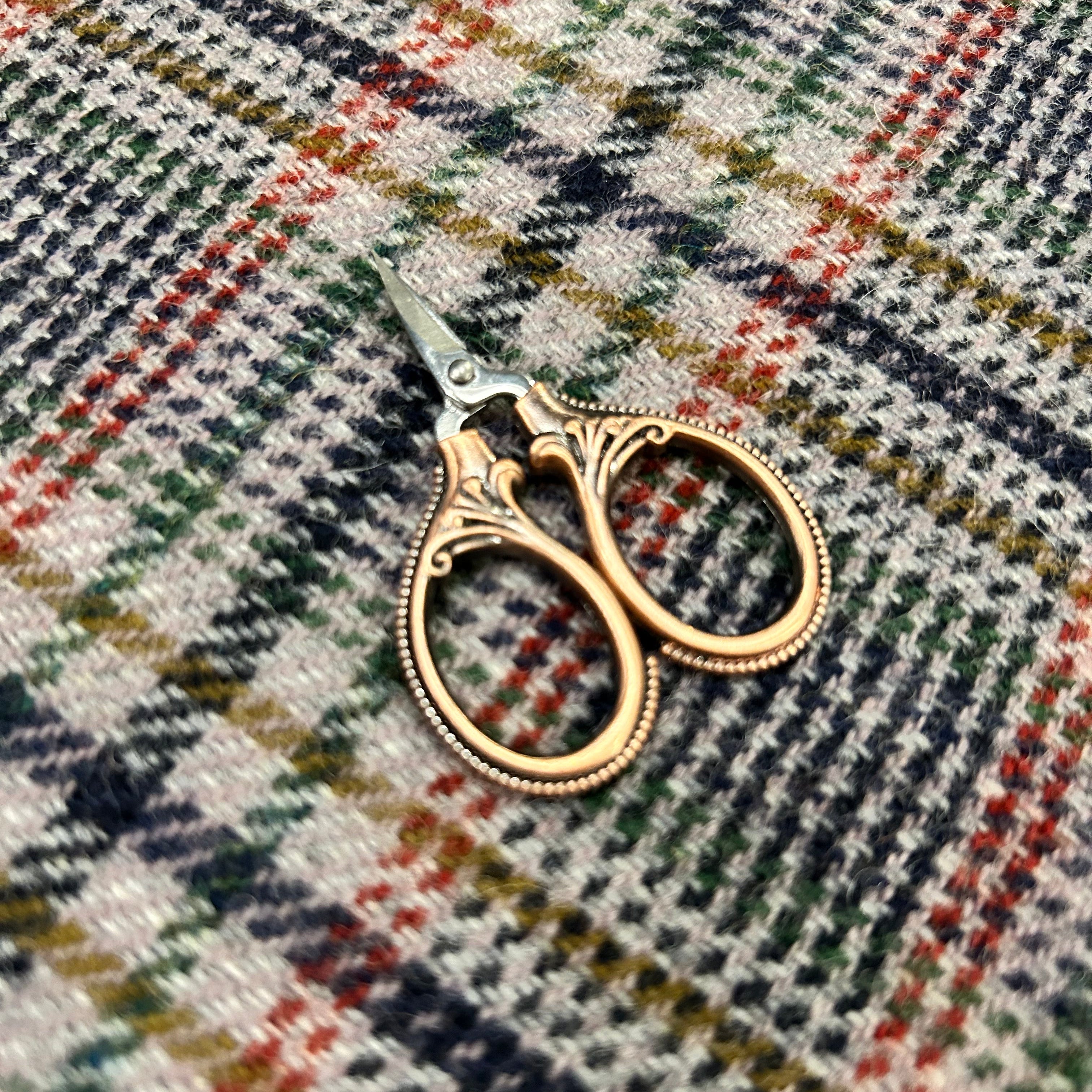 Decorative gold scissors on a plaid fabric background