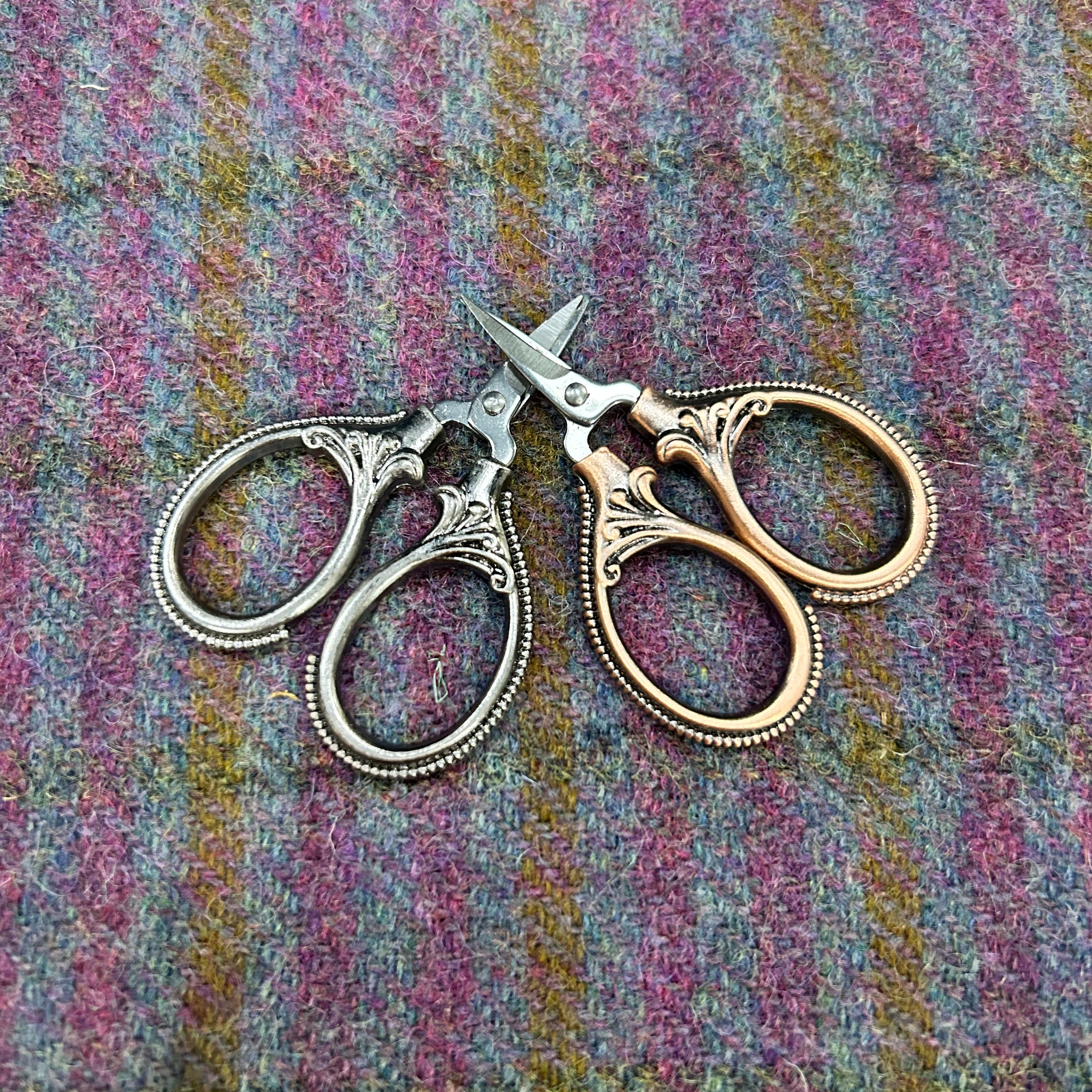 Pair of ornate scissors on a textured fabric background
