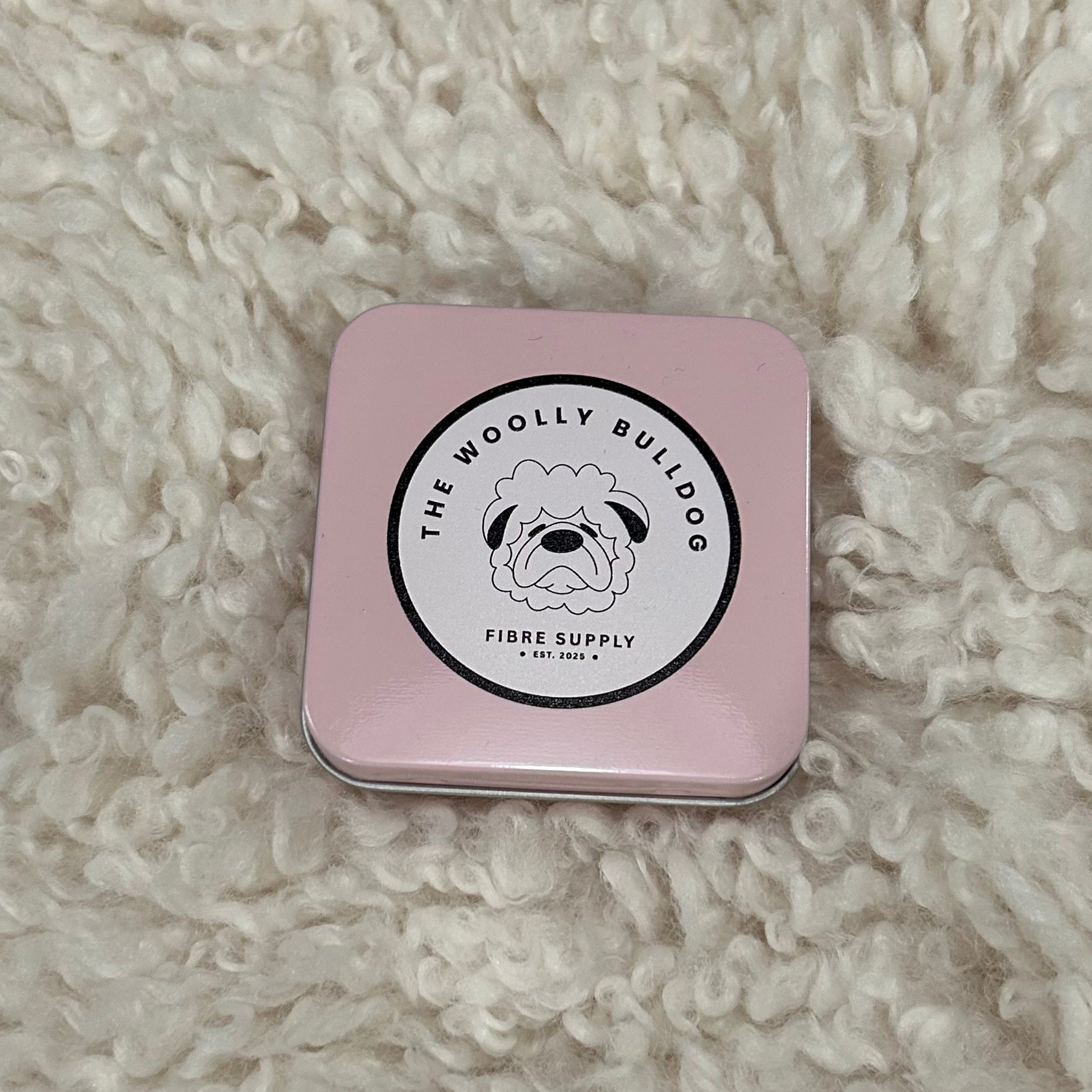 Pink tin with a brand logo on a fluffy white surface