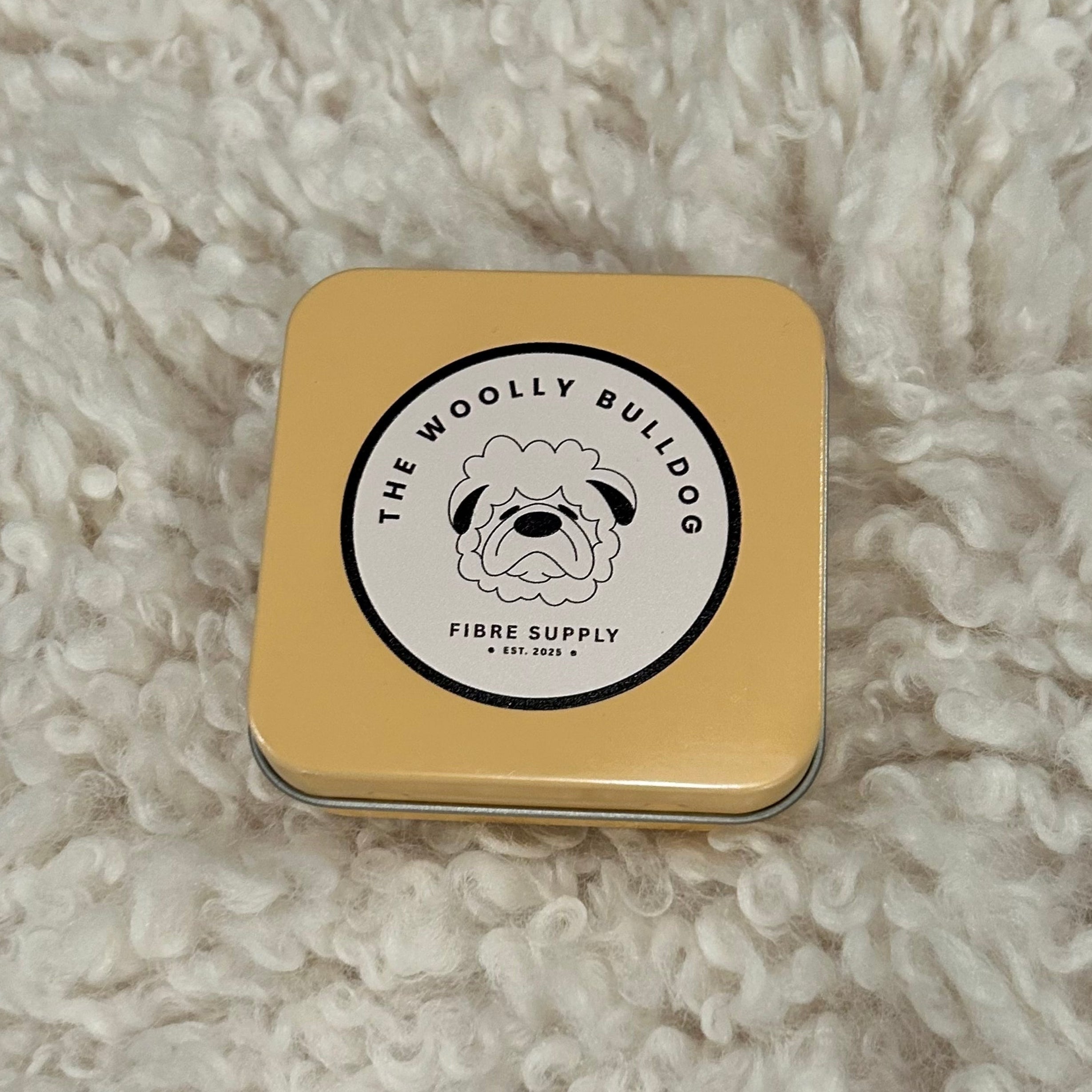 Gold tin with a logo on a textured beige surface