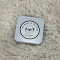 Square tin with a logo on a fluffy white surface