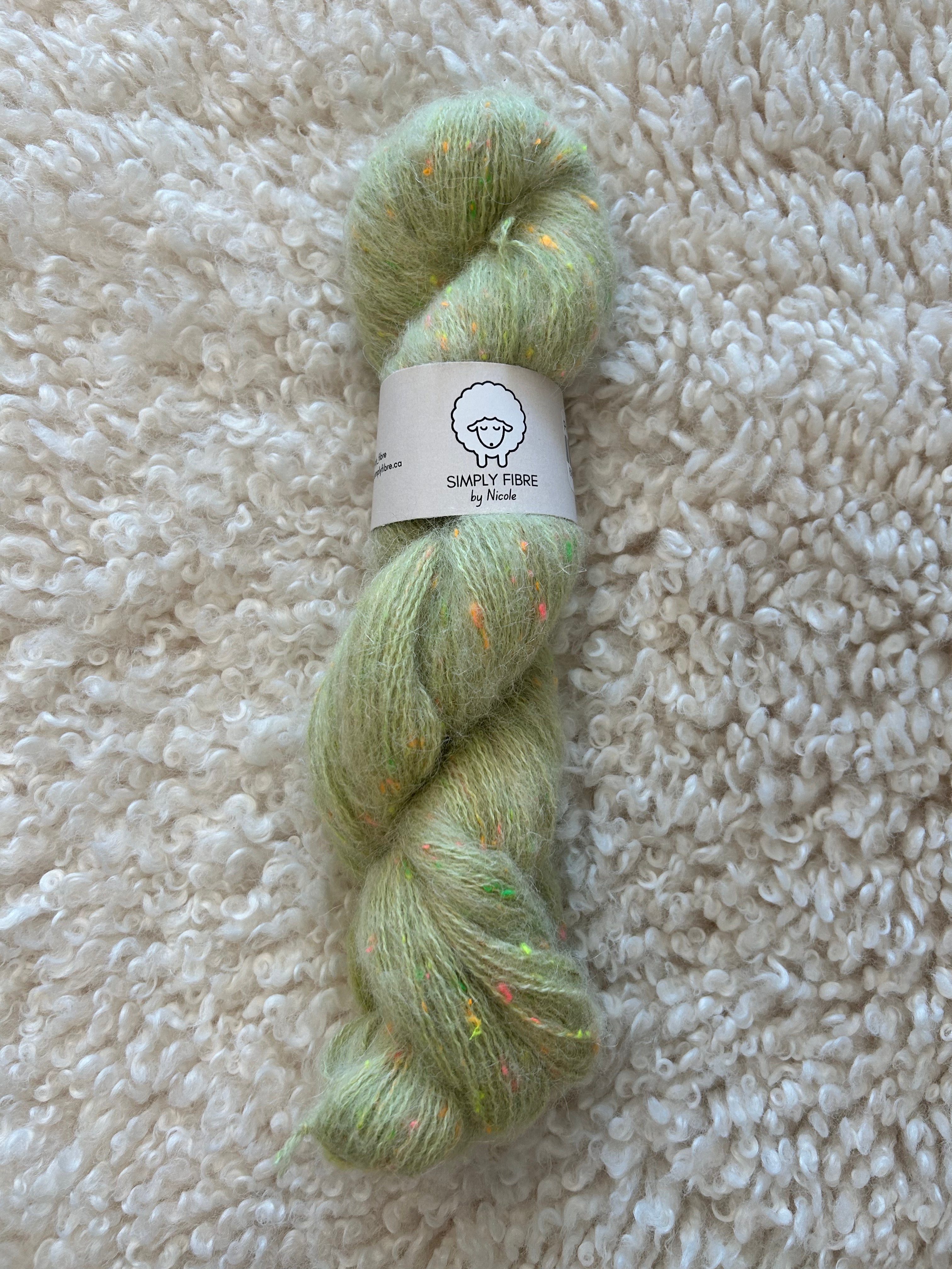 Green skein of yarn with a label on a textured beige surface