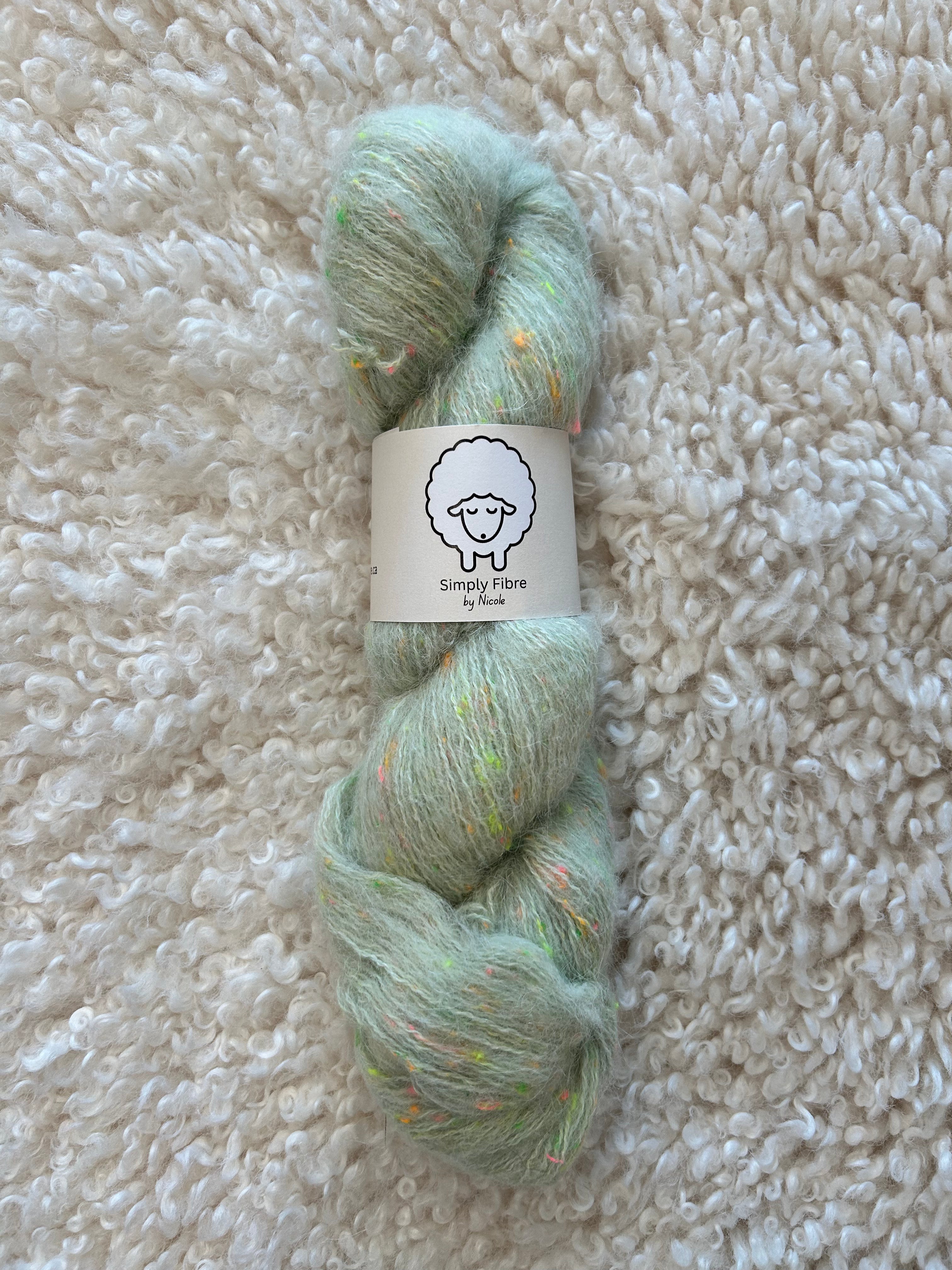 Light green skein of yarn with a label on a textured beige surface